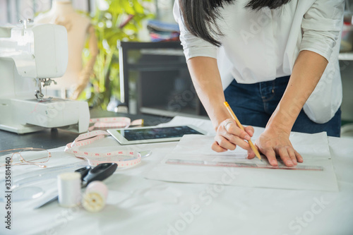 Young female fashion designer working on her designs in the studio. Fashion designer drawing sketches for new collection. Beautiful fashion woman designer drawing in studio .