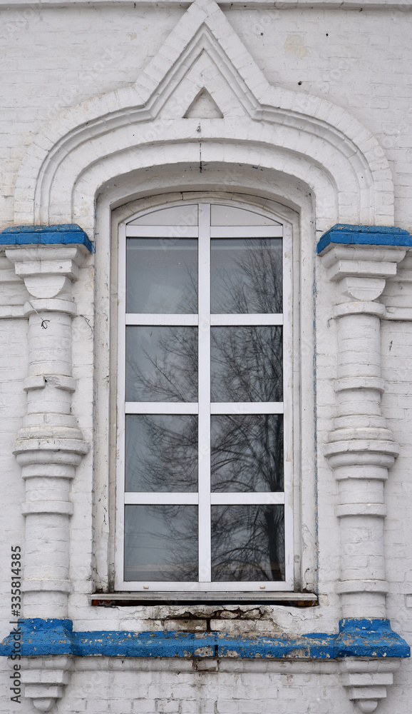 A large window in the church. A plastic frame framed by pillars of fancy stone moldings.