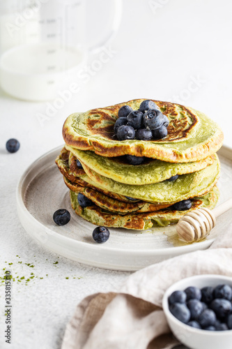 matcha pancakes on a white background with blueberries and honey vegan food