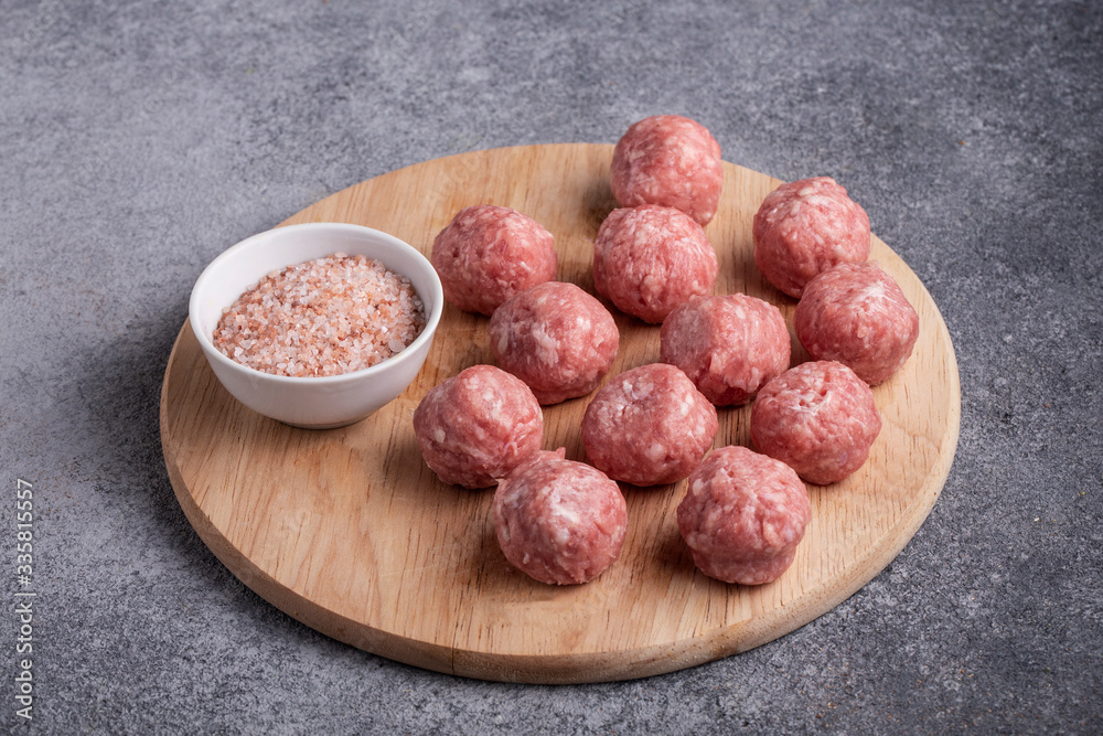 meatballs raw minced meat on a wooden Board pink salt grey background