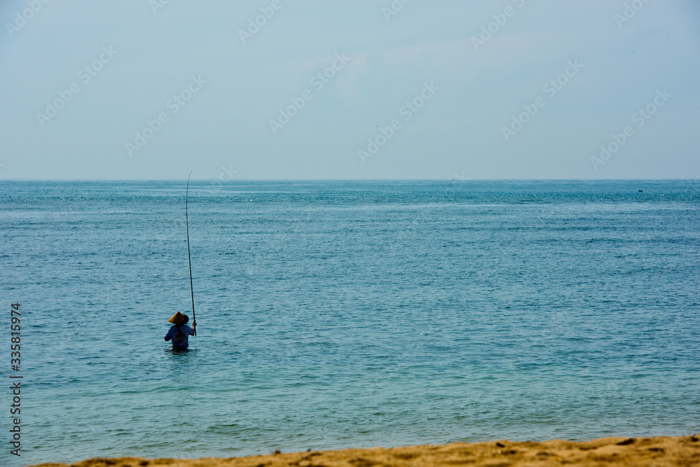 Traditional fisherman fishing rod catches the fish in the bay. Bali, Indonesia.