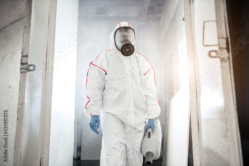 male in protective hazmat suit and gas-mask against coronavirus, disinfect areas, pathogen respiratory quarantine coronavirus COVID-19 concept © alfa27