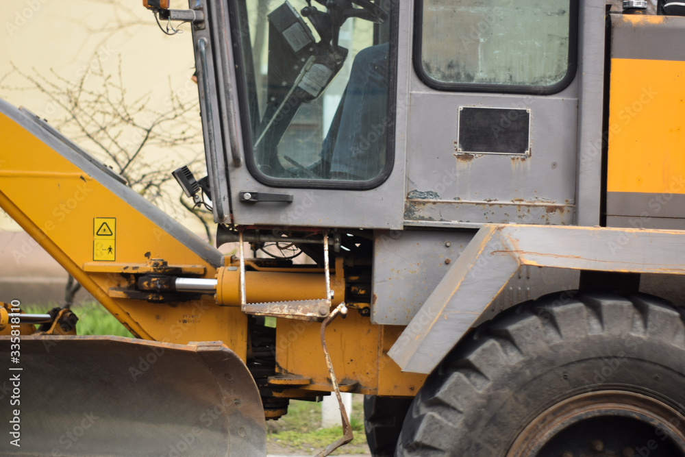 Yellow backhoe loader close up. Heavy duty machinery backhoe excavator on site. Backhoe loader in motion Yellow backhoe loader close up. Heavy duty machinery backhoe excavator on site. Backhoe loader in motion