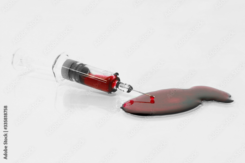 Isolated syringe have red blood inside with needle and some blood drop on floor on gray background, dark tone Isolated syringe have red blood inside with needle and some blood drop on floor on gray background, dark tone