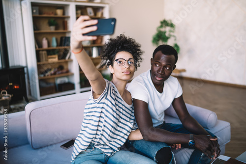 Young multiethnic couple taking selfie on couch