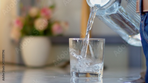 Man pouring water from a clear jug into a water glass