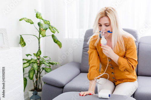 Tableau sur toile Portrait of adult woman using steam vapor inhaler nebulizer doing aerosol inhala