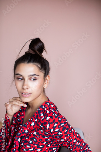 Portrait of a young beautiful woman in a red dress indoors.