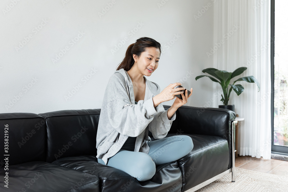 A young Asian woman using mobile phone in the living room