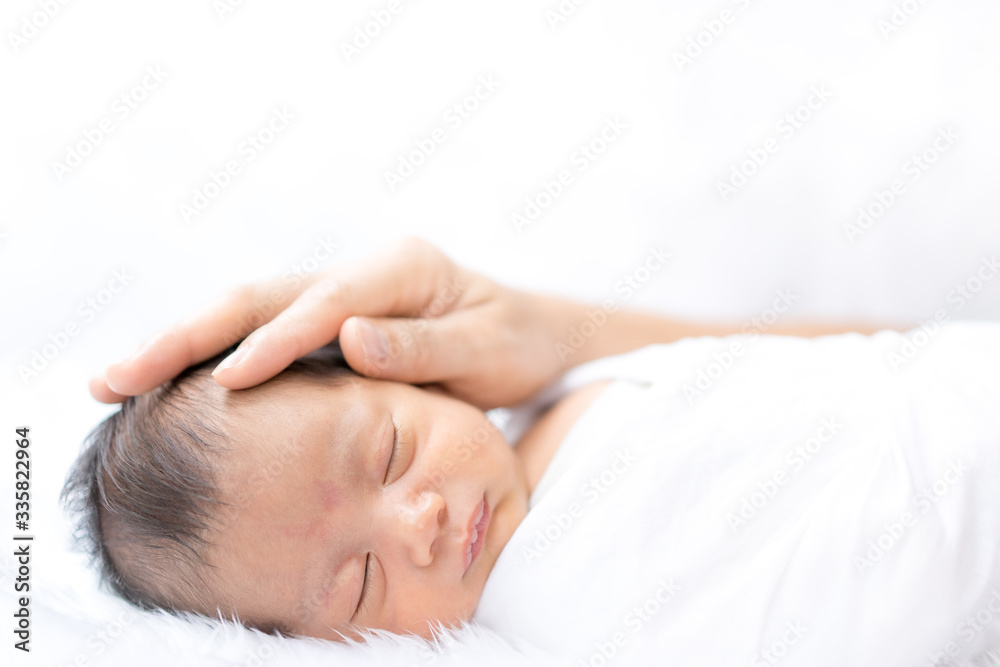 A cute sleeping newborn baby boy gentle touching by his parent's hand, concept of care and support of parent to their infant with love in family lifestyle. A cute sleeping newborn baby boy gentle touching by his parent's hand, concept of care and support of parent to their infant with love in family lifestyle.