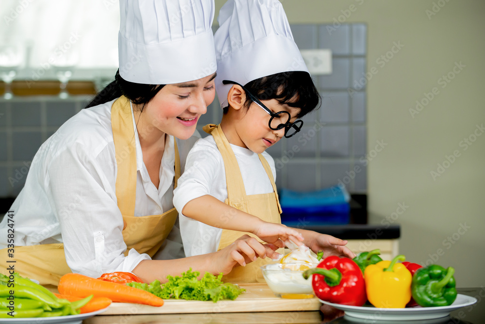 Happy Cute asian little boy with mother preparing cooking fresh salad in kitchen at home Happy Cute asian little boy with mother preparing cooking fresh salad in kitchen at home