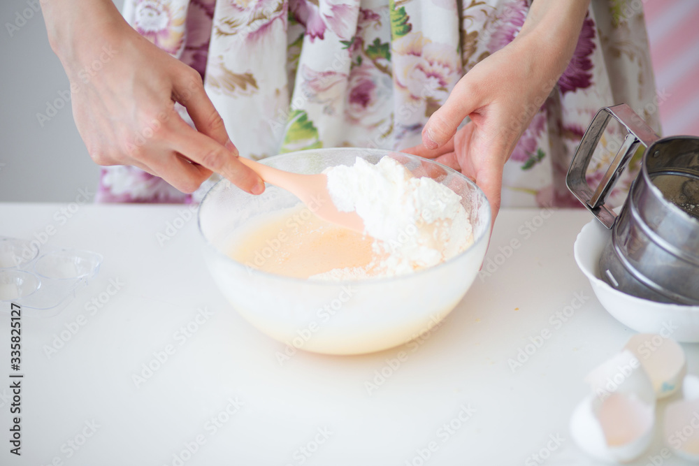 Female hands of a pastry chef whisk cream.Pastry chef whips cream light photo. Pink pastel background.