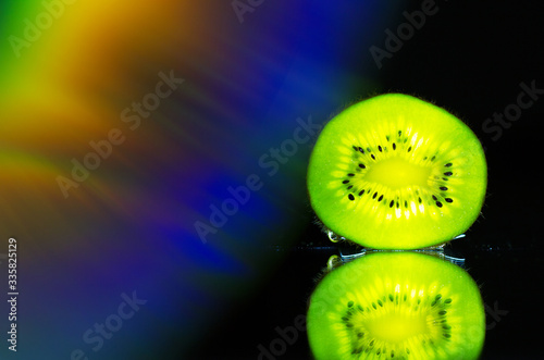 Kiwi illuminated by a flashlight on the mirror 

Photo taken at home, 4.04.2020, fruit, mirror, disk, water 