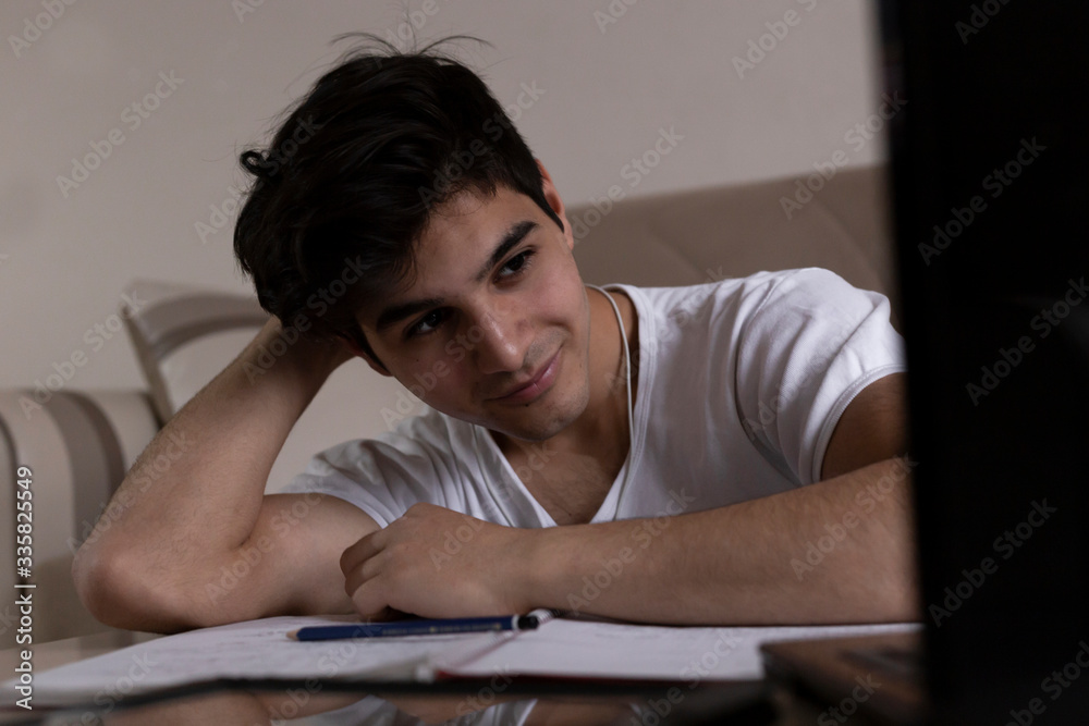 Teenage student studying at home using his tablet and computer Teenage student studying at home using his tablet and computer