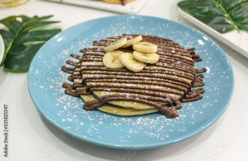Blue plate with pancakes with chocolate and banana