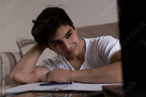 Teenage student studying at home using his tablet and computer