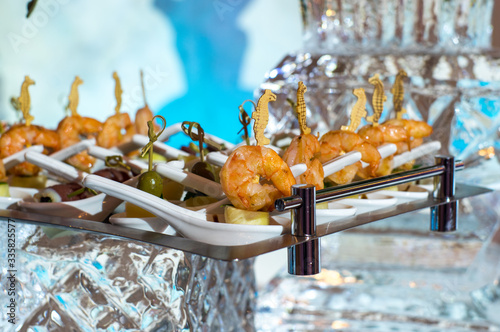 Shrimps for banquet on metal plate on ice construction