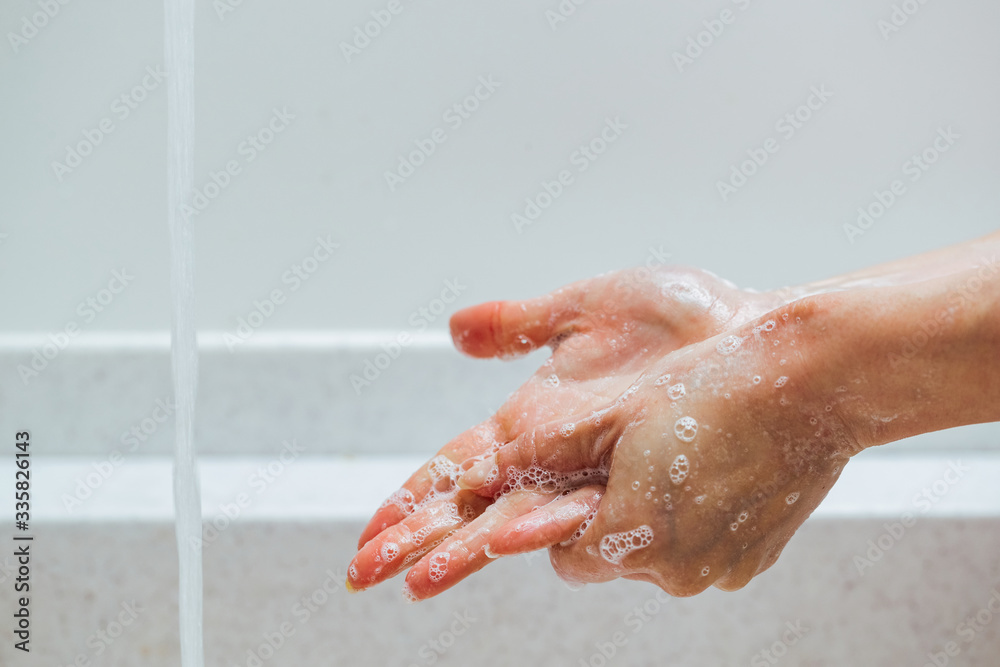 Fototapeta premium Close-up of woman rubbing hands with a soap under bathroom sink.