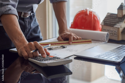 Architect man use calculating machine and blueprint at office.