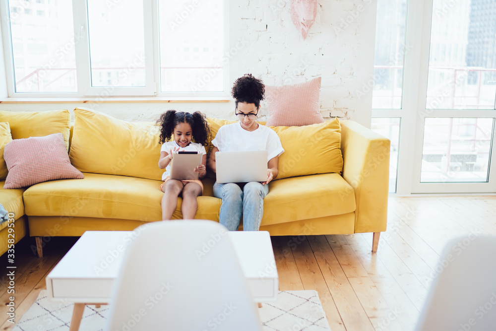 Daughter and mother sitting on sofa and using devices Daughter and mother sitting on sofa and using devices