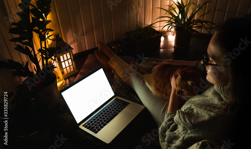 Woman with cat in the evening watching a show on a laptop