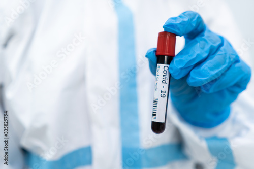 close up picture of doctor in personal protective equipment showing test tube of covid-19. coronavirus, analysis, blood sample, medical, healthcare concept 