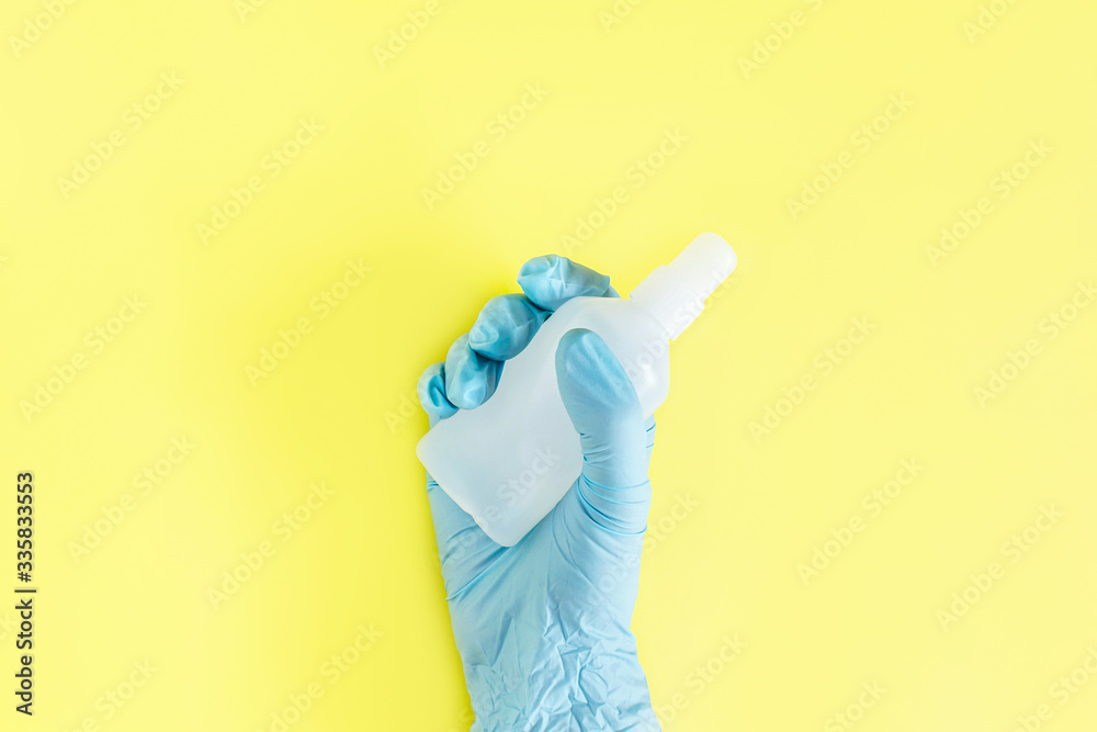 Human hand in rubber elastic glove with sanitizer bottle on yellow background. Concept of coronavirus protection, COVID-19 pandemic, global quarantine. Flat lay, top view. Copy space Human hand in rubber elastic glove with sanitizer bottle on yellow background. Concept of coronavirus protection, COVID-19 pandemic, global quarantine. Flat lay, top view. Copy space