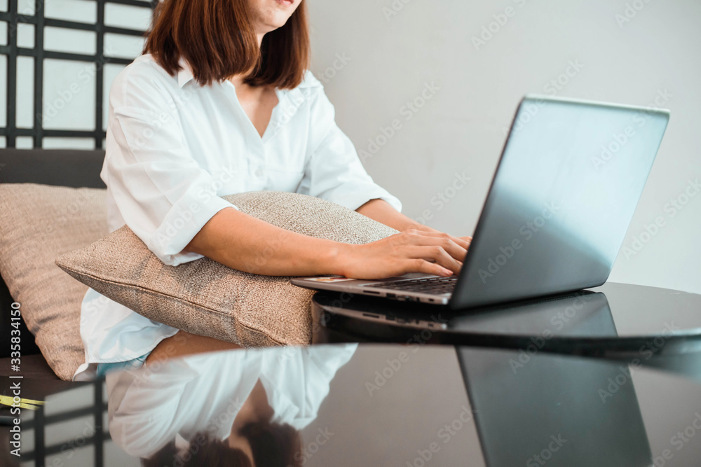  young woman working on laptop computer while sitting at the living room. work from home concept