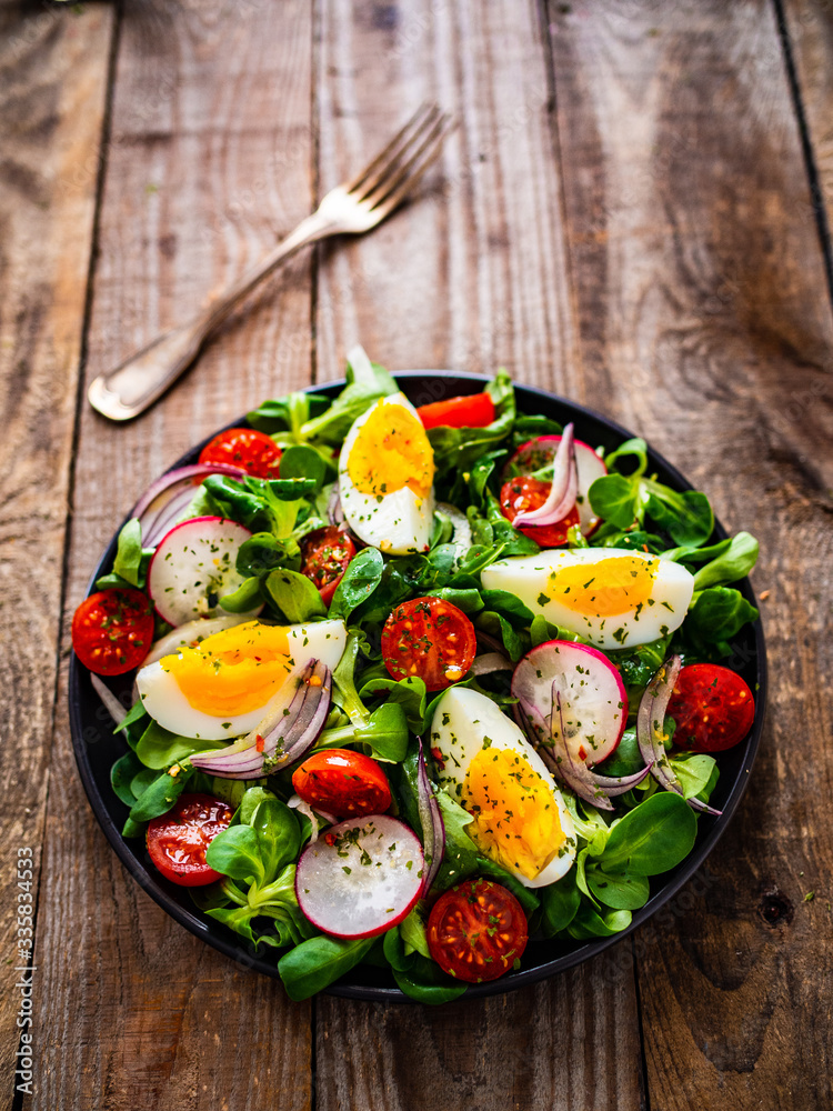 Salad with boiled egg and vegetables on wooden table
