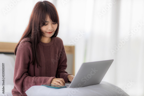 Asian woman using laptop for working, educational, e-commerce, social media in her bed. corovavirus covid-19, stay at home, work form home concept.
