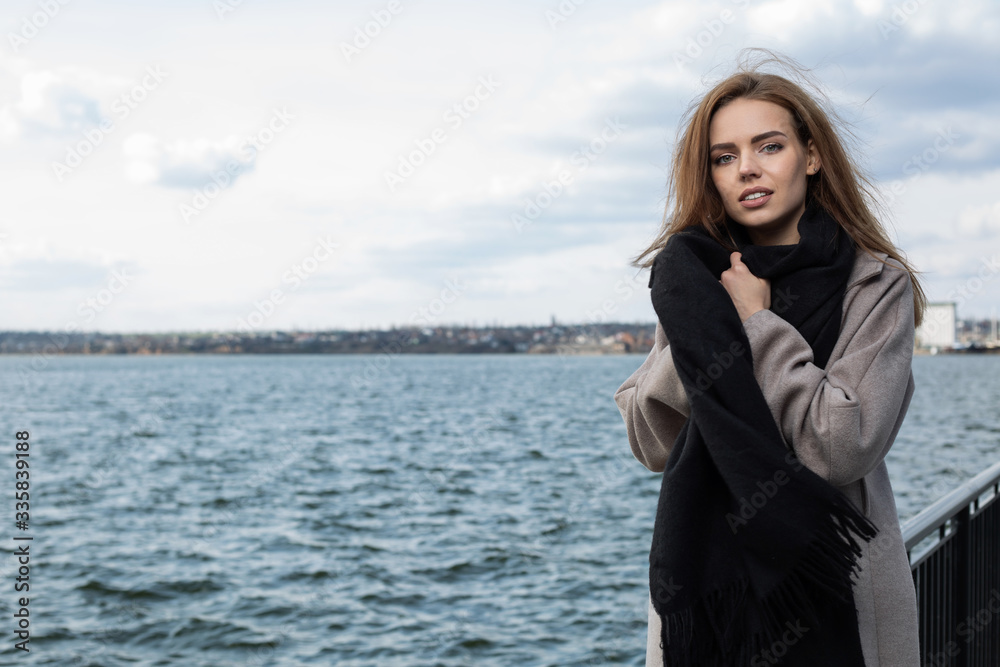 Pretty girl wraps herself in a scarf on the street