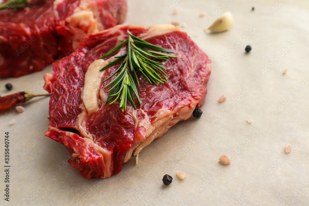 Tasty raw steaks with rosemary on light background
