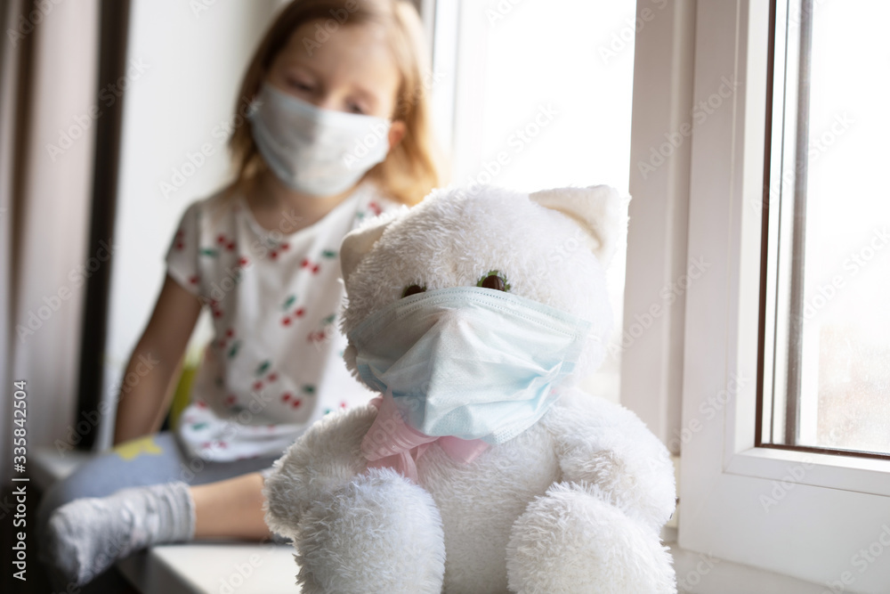 Sad child and his teddy bear both in protective medical masks. Children and illness COVID-2019 disease concept Sad child and his teddy bear both in protective medical masks. Children and illness COVID-2019 disease concept