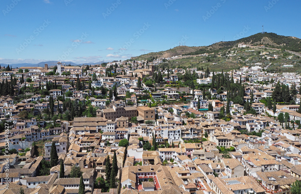 The cityscape with many far old buildings and far green-yellow hills on the sunny summer day