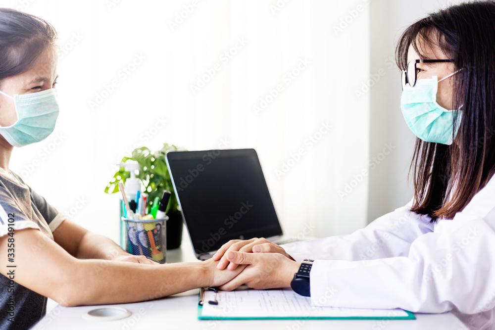 Doctor working in the office and holding patient's hands and comforting her Doctor working in the office and holding patient's hands and comforting her