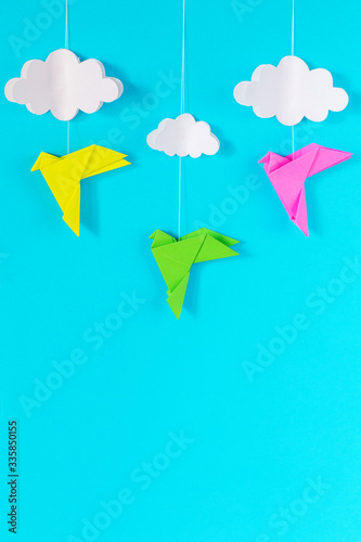 blue background with colorful birds and white clouds on a rope of paper