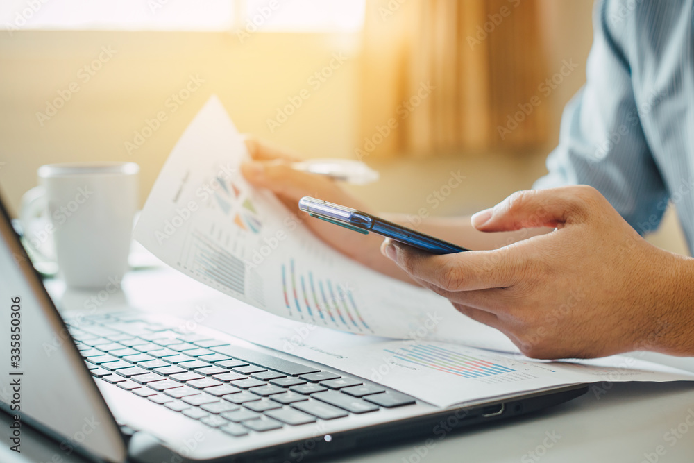 Φωτογραφία Young businessman working at home office living spaces for investment analyzing company financial report balance with laptop computer and smart phone