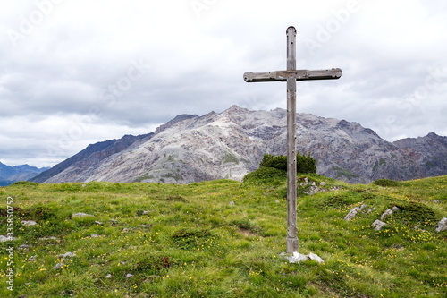 Cross on top of the mountains of Livigno Alps on the border between Italy and Switzerland, cloudy summer day, Italy
