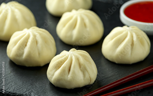 Steamed Buns with duck stuffing, chili sauce on rustic stone board. Asian food