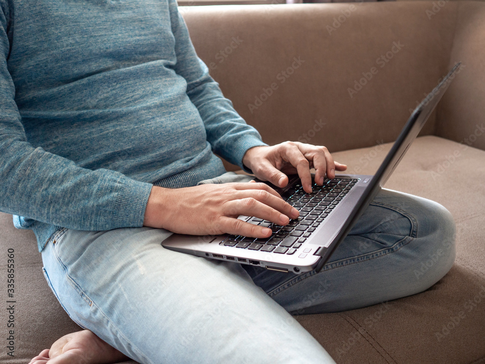 Naklejka premium Working from home. Close up male hands printing on laptop at home. Concept of business, quarantine, isolation, work at home, coronavirus.