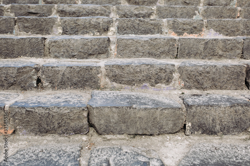 Stone stairs made of gray rough old stone on the street of a European town. Granite staircase background close up, urban details