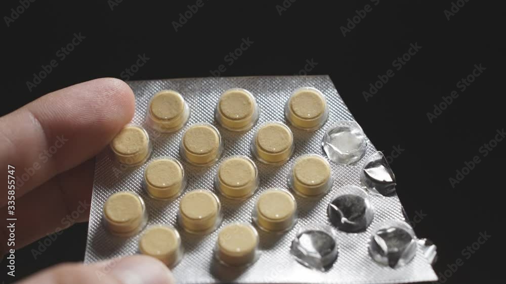 Close-up of a man's hand on a dark background holding a pack of medical pills on a blister. covid-19. Close-up of a man's hand on a dark background holding a pack of medical pills on a blister. covid-19.