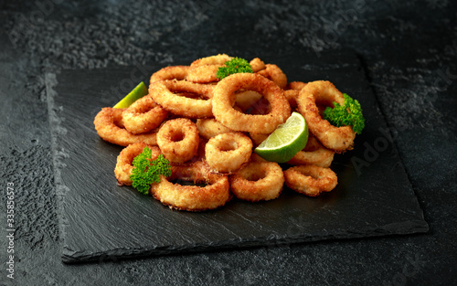 Konstfotografi Oven baked breaded calamari rings served with lime wedges, sweet chilli sauce an