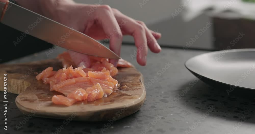Slow motion man hands chopping salted trout with knife on olive wood board Slow motion man hands chopping salted trout with knife on olive wood board
