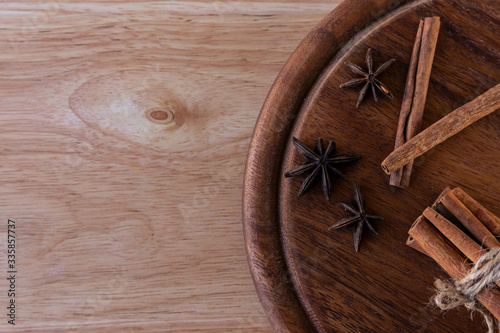 Three stars of star anise, cinnamon separately and in a bunch lie on a dark brown wooden board, on a light brown board. Great background for a cafe or restaurant menu