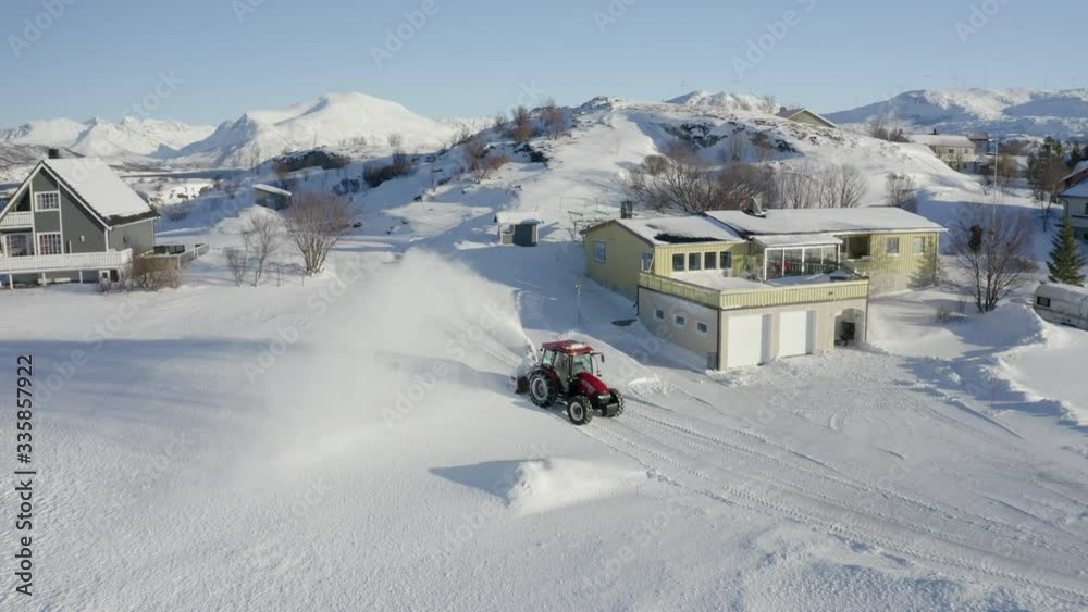 A Tractor Pulls a Snowblower Along to Clear a Road in the Wintery Landscape of Norway A Tractor Pulls a Snowblower Along to Clear a Road in the Wintery Landscape of Norway
