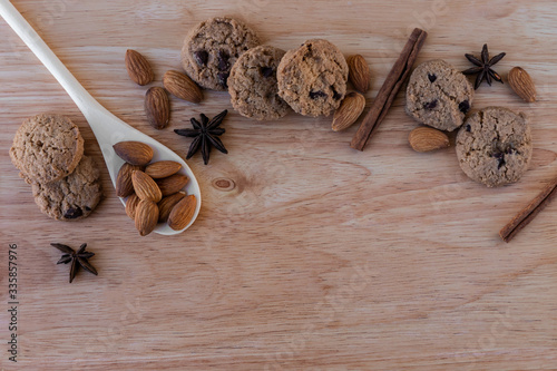 Ð¡ookies with chocolate, cinnamon and almonds with star anise star, white wooden spoon, on a light brown wooden board. Great background for a cafe or restaurant menu, signboard photo