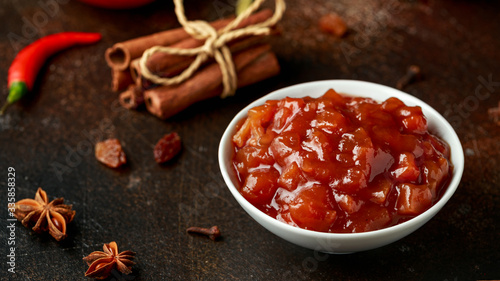Homemade apple and chilli chutney with spices on dark background photo