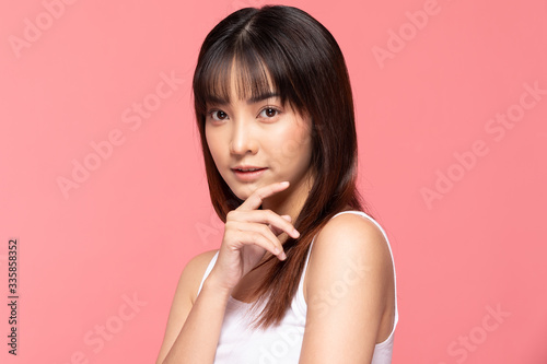 Young Beautiful Asian woman smile touching chin with clean and fresh skin Happiness and cheerful with positive emotional,isolated on pink background,Beauty Cosmetics and spa Treatment Concept