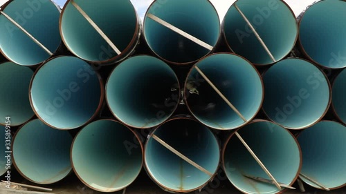 View through metal pipes of large diameter. Metal pipes of large diameter in a metal warehouse, large pipes in an open-air warehouse, large diameter pipes stacked in rows photo